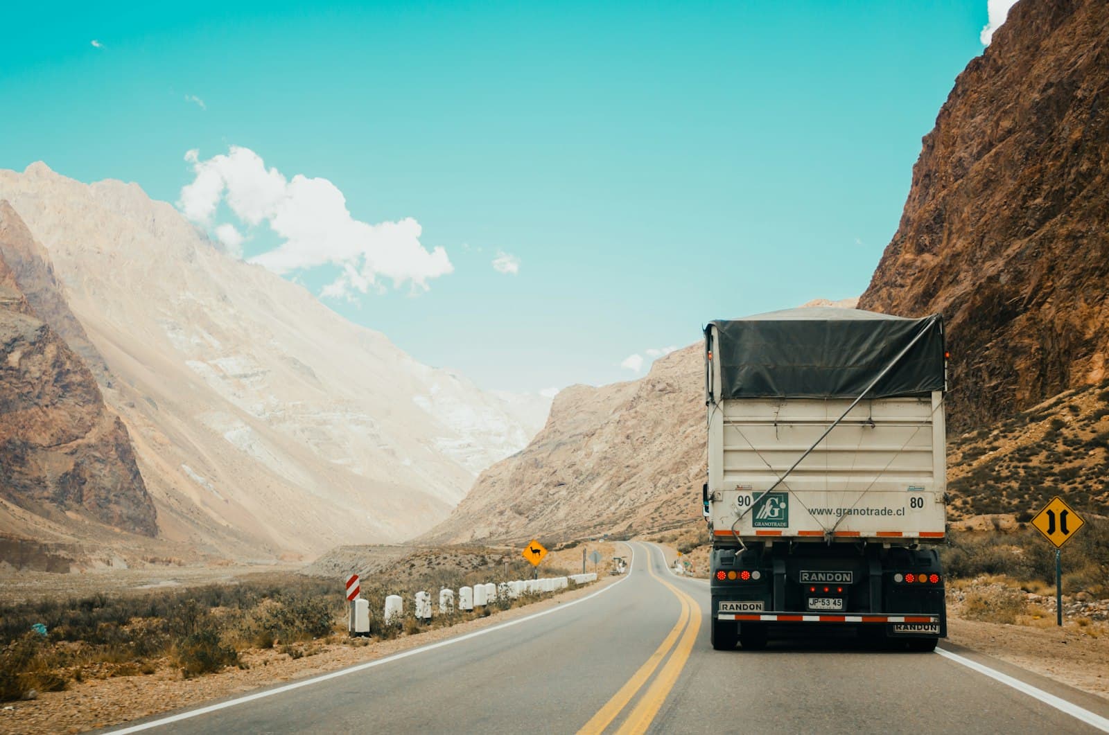 Tráiler de carga circulando por una carretera entre montañas